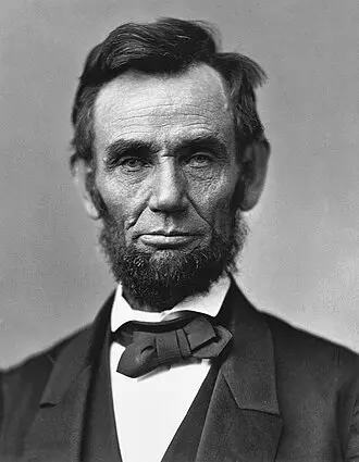 A statue of young Lincoln sitting on a stump, holding a book open on his lap