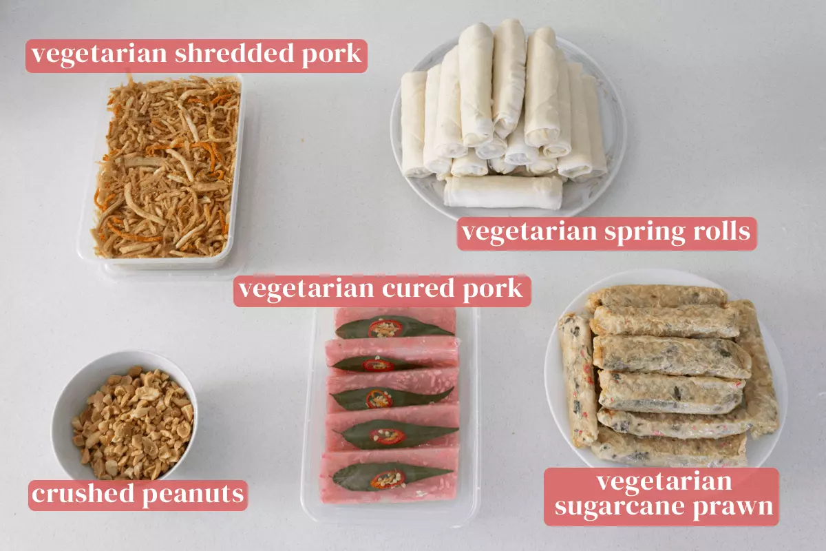 Vegetarian shredded pork, spring rolls, sugarcane prawns and cured pork along with crushed roasted peanuts in a bowl.