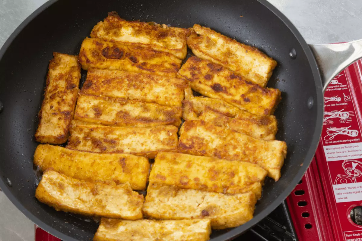 Marinated tofu searing in a pan.