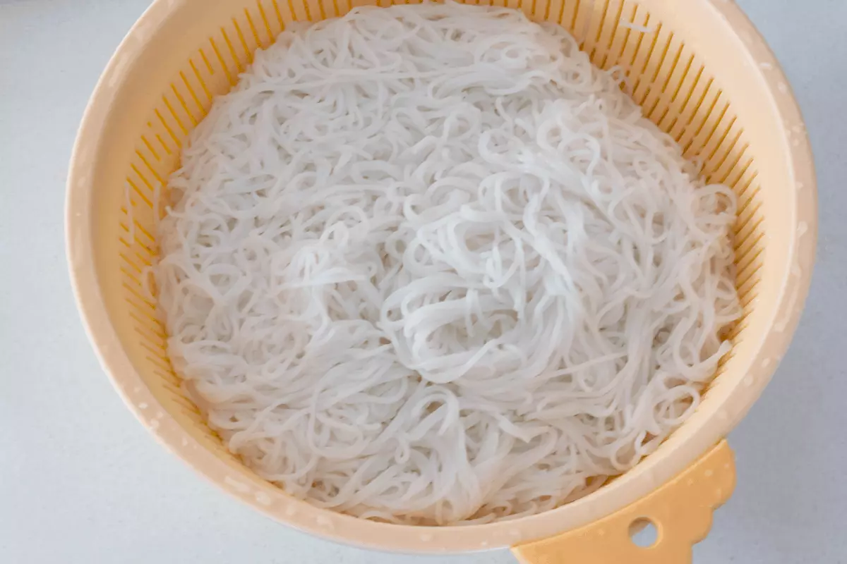 Cooked rice noodles in a colander.