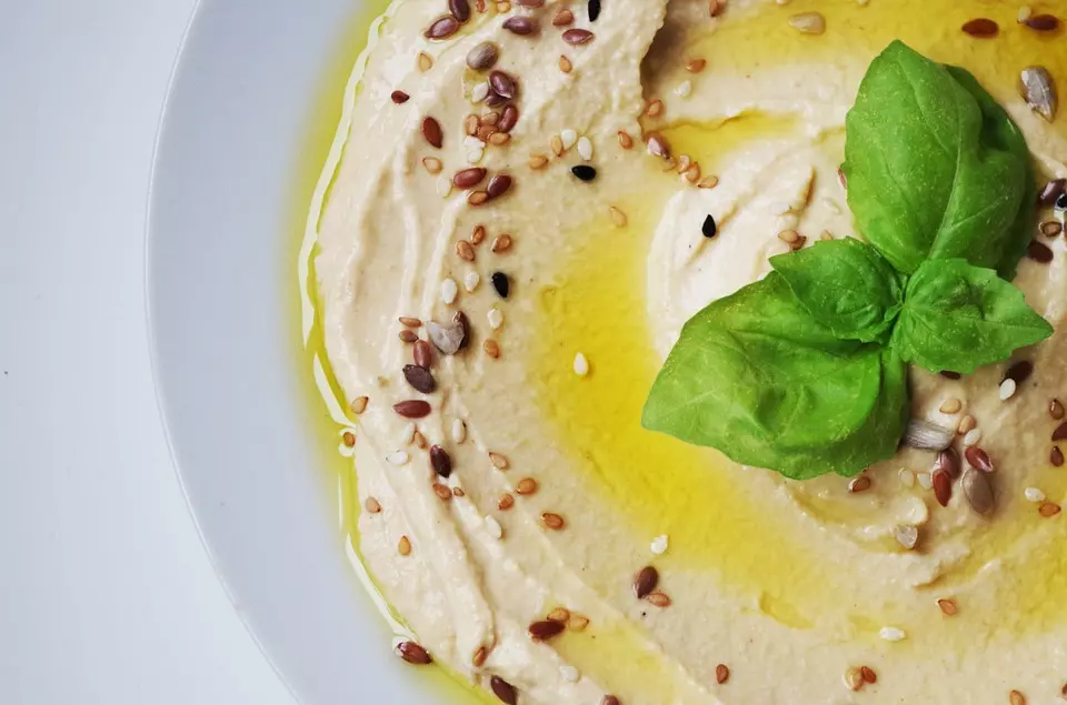 đĩa hummus vàng với lá gia vị trang trí